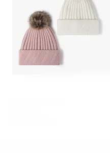 Detail of pink and white knitted beanies featuring soft pom-poms and ribbed knit patterns