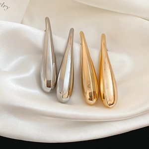 Macro shot of minimalist teardrop earrings in polished gold and silver metal finishes