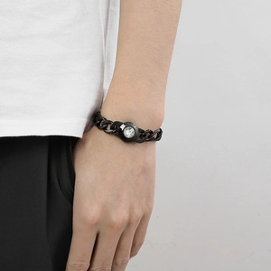 Detail of a black titanium steel chain bracelet with a crystal-encrusted round clasp on wrist