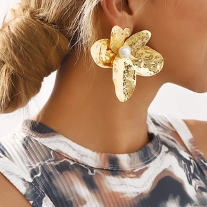 Hammered gold flower earrings with a pearl center shown on a model side profile