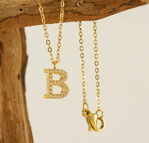 Close-up of a gold titanium steel necklace with a sparkling diamond-set letter B pendant