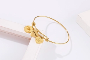 Detail of adjustable gold bangle with engraved family silhouette, MOM and Love heart charms