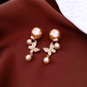 Vue macro des boucles d'oreilles perles papillon plaquées or 18k sur soie rouge