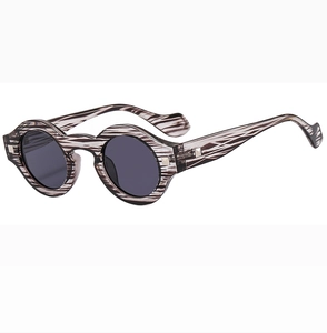 Detail of round sunglasses with black and white striped texture and metal hinges