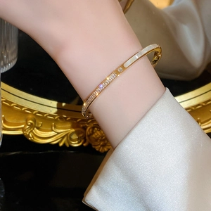 Dettaglio di un bracciale placcato oro con zirconi e intarsio in madreperla sul polso