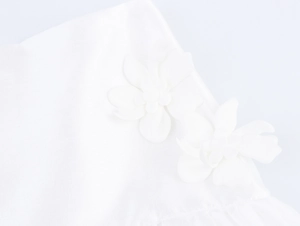 Detail of white two-piece set featuring delicate 3D floral accents on textured fabric