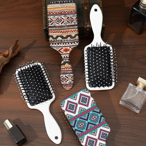 Bohemian pattern air cushion hairbrushes with massaging bristles on dark wood surface