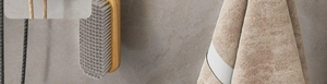 Close-up of minimalist wooden handle cleaning brush and beige towel on a grey stone surface