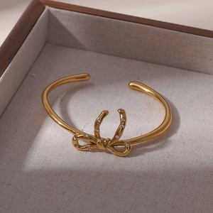 Gros plan détaillé d'un bracelet jonc ouvert en forme de nœud doré orné de strass brillants