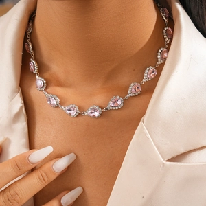 Gros plan de colliers en cristal rose sur un mannequin en blazer blanc chic