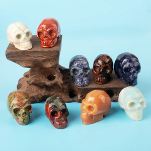 Detailed view of nine diverse natural gemstone skull carvings on a wooden display stand