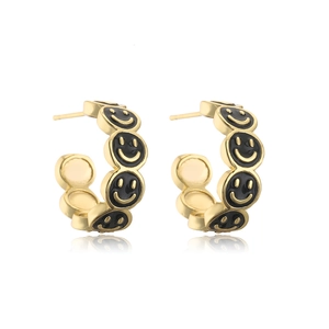 Macro shot of 18K gold plated C-shaped earrings with black enamel smiley face patterns