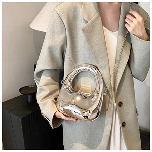 Silver metallic acrylic handbag with irregular design worn with a sage green blazer