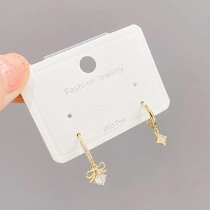 Pendientes asimétricos dorados con lazo, estrella y circón en postes de plata S925