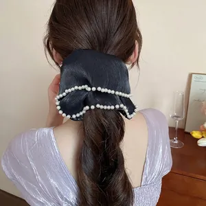 Elegant black satin bow hair tie with pearl edges worn on a braided ponytail