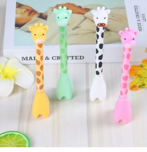 Close-up of cute cartoon giraffe pens in yellow green white and pink standing on desk