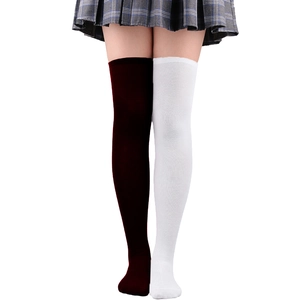 Détail de chaussettes montantes bicolores rouge et blanc avec jupe à carreaux