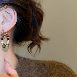 Close-up of retro beaded hoop earrings with tiger eye and green stone on model