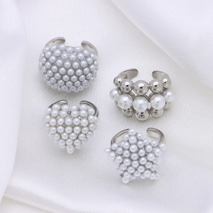 Elegant adjustable pearl rings in heart and star shapes on white silk background