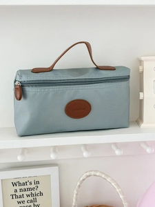 Close-up of Morandi blue nylon toiletry bag with leather handle and embossed logo detail