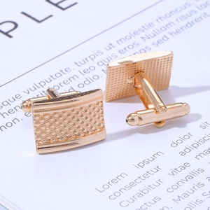 Macro shot of gold square cufflinks with fine grid texture on vintage paper