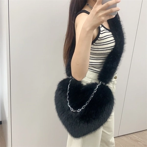Detail of a black plush heart-shaped crossbody bag with a silver metal chain accent