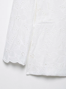 Détail de la broderie romantique blanche et de la texture ajourée sur la veste femme