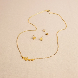 Detail view of golden stainless steel jewelry set with star necklace and stud earrings