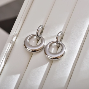 Close-up of interlocking polished stainless steel double hoop earrings on white leather
