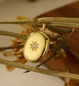 Macro detail of a gold oval starburst locket featuring a sparkling zircon stone centerpiece