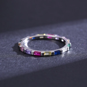 Anello in argento minimalista con gemme arcobaleno su sfondo scuro testurizzato
