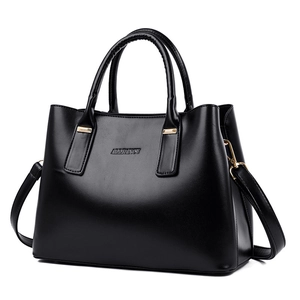 Minimalist black leather handbag with gold hardware and dual handles on white background