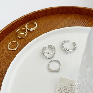 Minimalist gold and silver rings and ear clips displayed on a white plate and wood tray