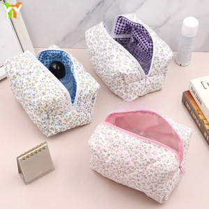 Detailed macro view of quilted floral makeup bags in blue, purple, and pink cotton fabric