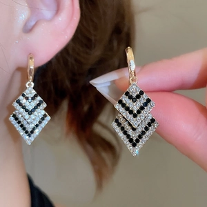 Gros plan de boucles d'oreilles losanges élégantes pavées de diamants noirs et blancs