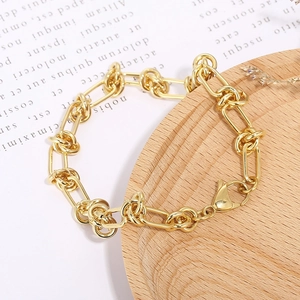 Gold-finish chunky knotted link chain bracelet displayed on a rustic wooden plate