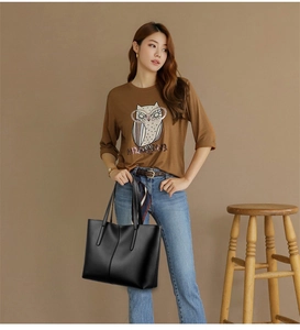 Detail of black faux leather tote bag with vertical stitching and dual top handles