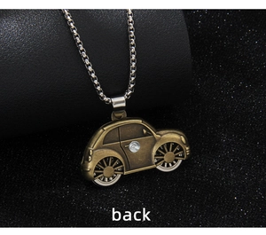 Macro shot of vintage bronze car pendant with silver box chain on black textured background