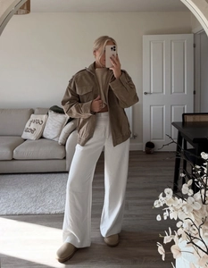 Brown faux suede jacket styled with beige knit top and white wide-leg trousers