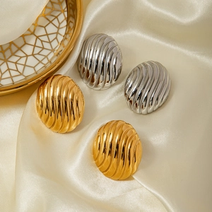 Vue détaillée de boucles d'oreilles clips dorées et argentées sur soie beige satinée