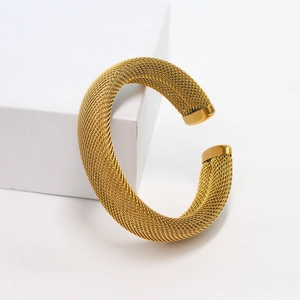 Detailed macro view of golden mesh woven stainless steel bracelet on white pedestal