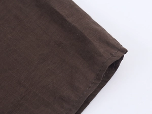 Détail de la texture coton marron avec coutures précises au poignet ou à l'ourlet