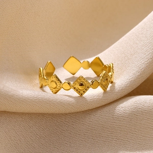 Macro detail of gold geometric open ring featuring textured diamond and dot patterns