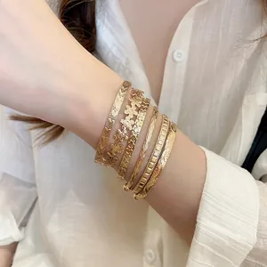 Élégant ensemble de 6 joncs dorés avec fleurs et étoiles sur le poignet d'un modèle