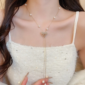 Detailed close-up of 18k gold plated necklace with zircon bow and elegant pearl tassels