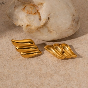 Detail shot of gold 18k stainless steel earrings with wavy texture on stone background
