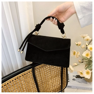 Detail of black faux suede crossbody bag with twisted rope handle and gold hardware