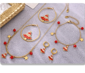 Detail view of gold stainless steel Christmas tree jewelry set on grey plush surface