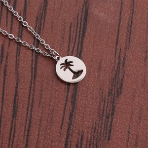Polished stainless steel necklace with a hollow coconut tree pendant on a wooden surface