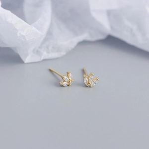 Detail of gold marquise-cut crystal leaf stud earrings on soft textured background
